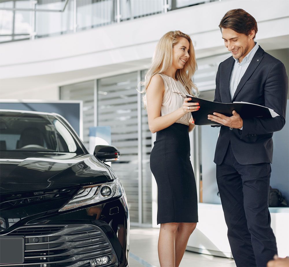 Customer and salesman reviewing paperwork beside a car