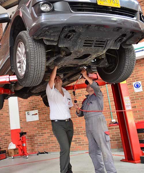 Technicians inspecting the underside of a car on a lift